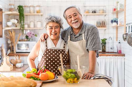Happy Asian senior couple cooking in their kitchen.