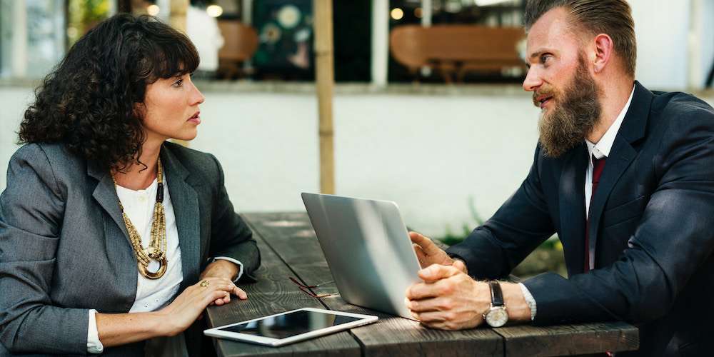 Man interviewing a woman for an executive position with benefits including a business owner insurance policy.