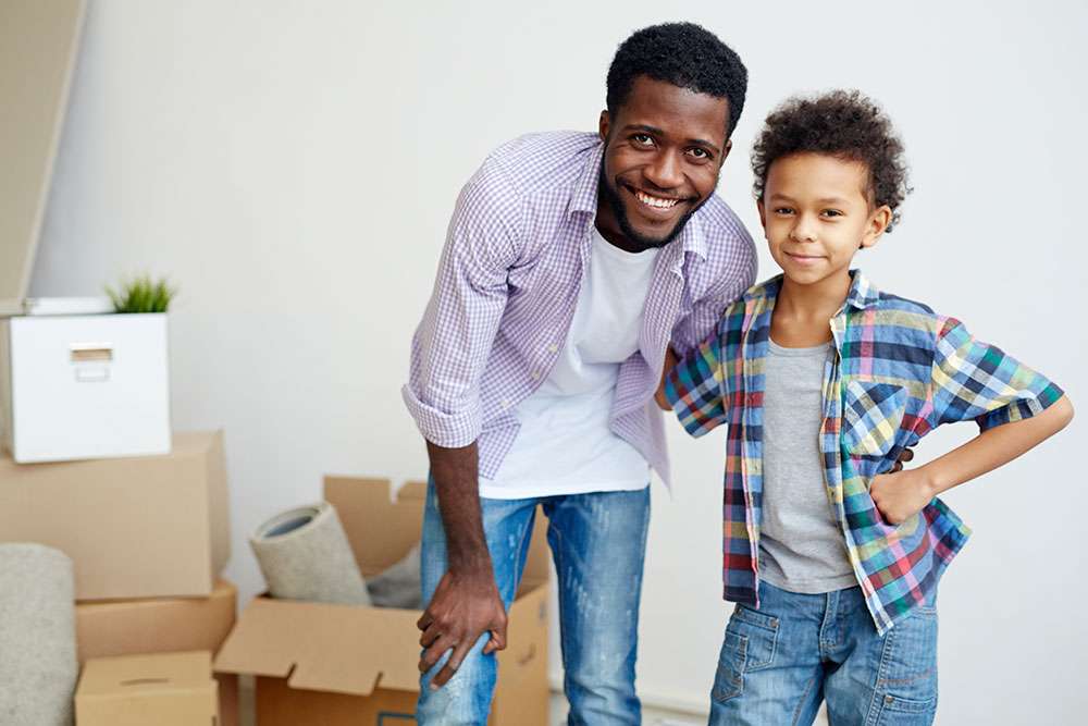 Young Black father and son, smiling because their family is protected with term life insurance no exam.