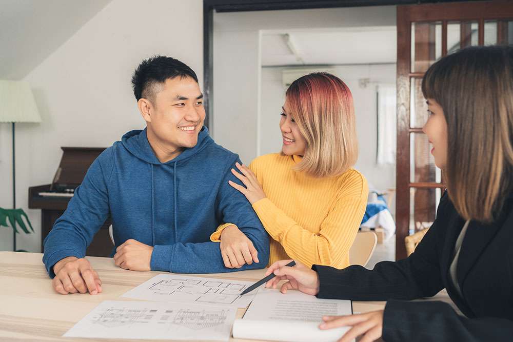 A young Asian couple with their agent, smiling and being happy customers.