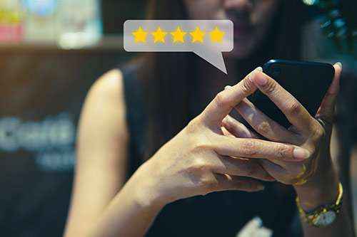Woman leaving a five-star review for a term life insurance company on her phone.