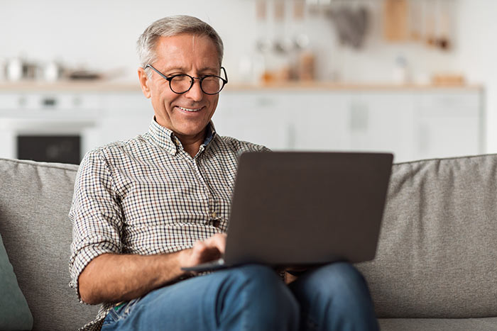 Senior man using a laptop to look up modified whole life insurance quotes.