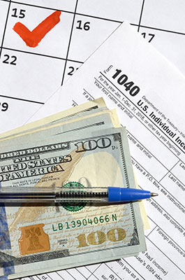 Collage of items related to taxes: a calendar, an IRS form, a stack of money, and a pen.