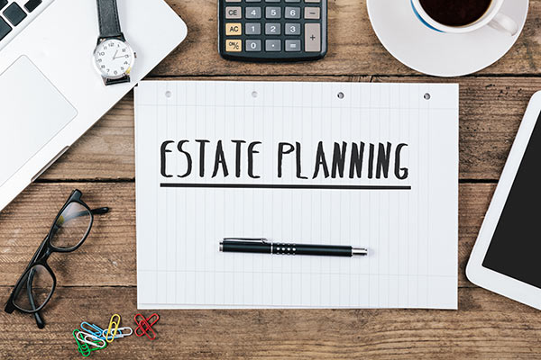 Note pad on desk with text written on it: Estate Planning