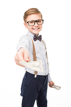 Cute little boy wearing glasses and suspenders holding out money to you.