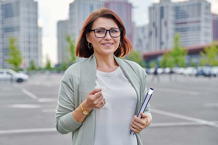 Businesswoman in her 40s standing outside, smiling at the camera