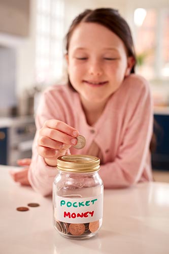 Girl putting coins into a jar to save for later