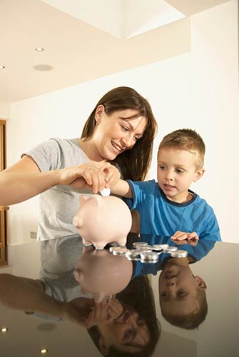 Mom and son putting coins in a piggy bank.