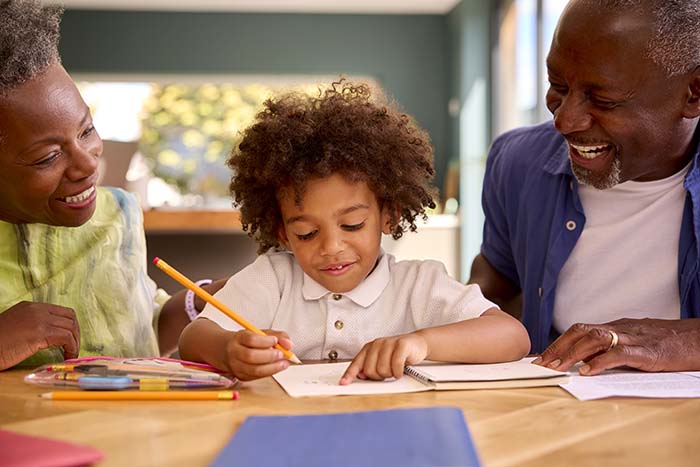 Grandparents help their grandson with his homework at the kitchen table
