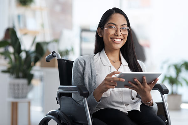 Successful businesswoman in a wheelchair using a tablet to get a quote for a million dollar whole life insurance policy.