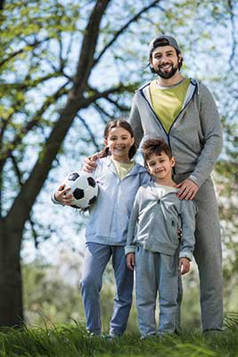 Dad and two kids playing soccer outside