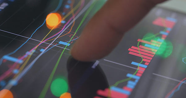 Close-up of a finger on a touchscreen using charts to analyze a stock market investment