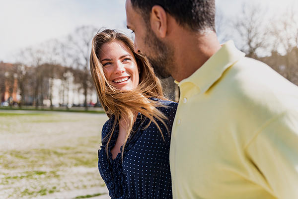 Woman walking with her boyfriend outdoors, holding hands and smiling
