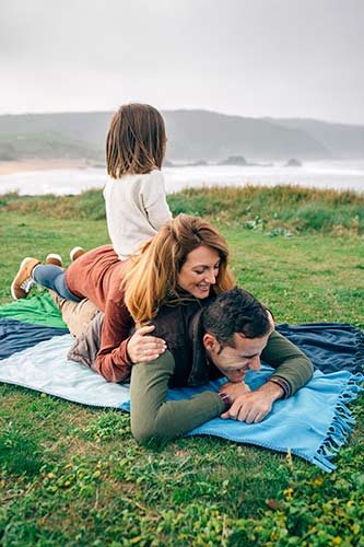Family laying on a blanket together in a chilly coastline park
