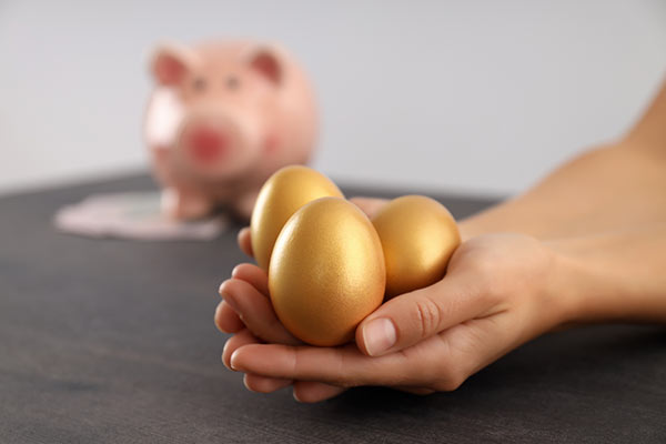 Hand holding three golden eggs, symbolizing the concept of how to use whole life insurance to create wealth