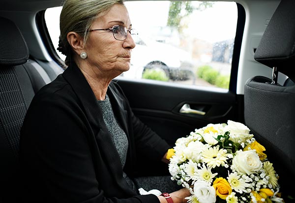 Woman wearing black in a car on the way to a funeral