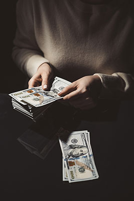 Woman holding a thick stack of hundred dollar bills