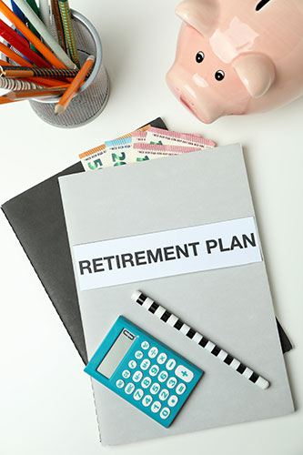 Folder labeled Retirement Plan with a calculator and piggy bank nearby, symbolizing the concept of LIRP, or life insurance retirement planning.