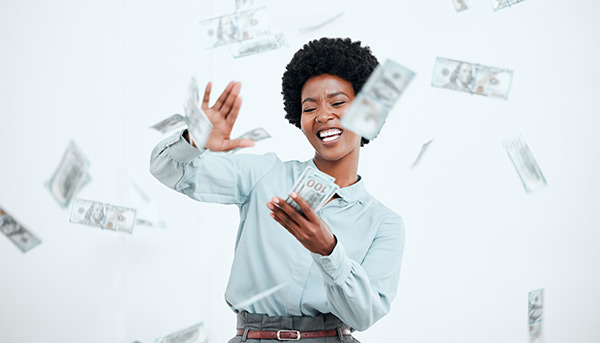 Woman smiling and holding money as dollar bills fall from the sky around her