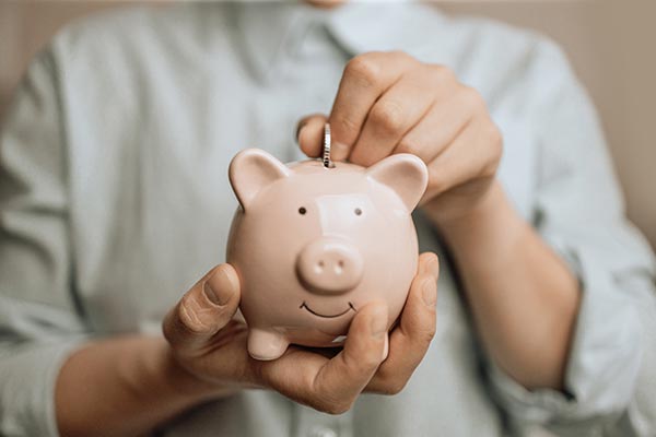 Woman putting a coin in a piggy bank, symbolizing whole life insurance’s cash value