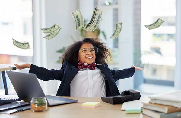 Smiling little girl wearing business clothes in an office as cash rains down on her