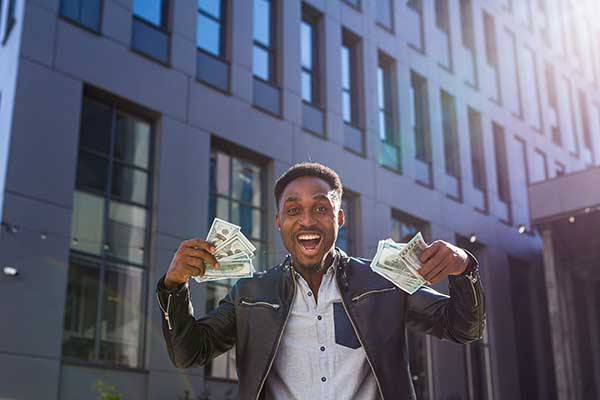 Successful businessman smiling as he holds handfuls of money