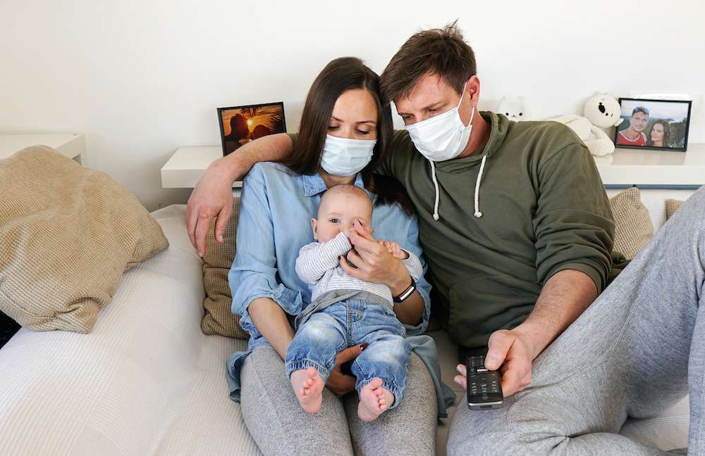 A mother, father, and baby on the couch, wondering how to get life insurance.