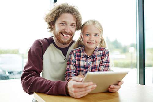 Dad and daughter using a laptop together.