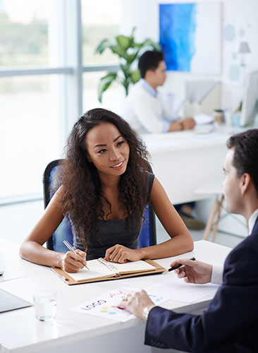 Life insurance agent sitting at her desk, helping a client.