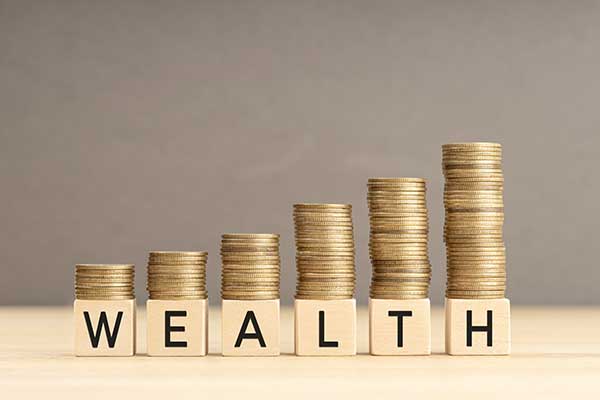 Coins stacked on blocks that spell out ‘wealth’