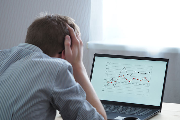 A stressed-out man sitting at his computer looking at stock market charts