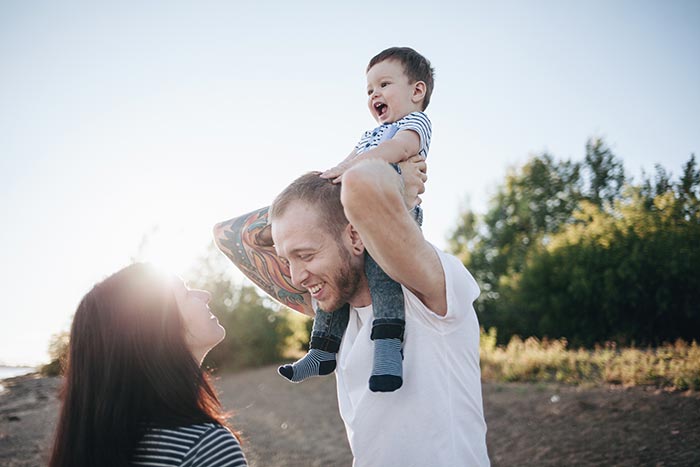 Young family of three - mother, father, and baby - playing at the beach