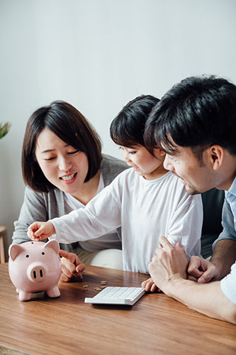 parents-and-daughter-saving-money-for-life-insurance-paid-up-additions Parents watching as their daughter puts money in a piggy bank for future life insurance paid up additions.