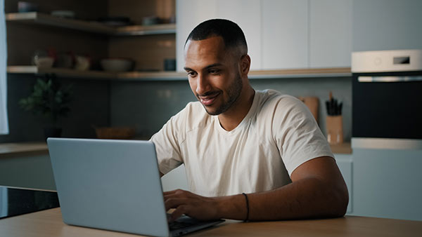 Young man at home using his laptop to research the question, what is third party life insurance?