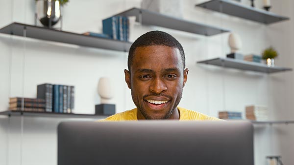 Man using his laptop to answer the question, "Can term life insurance be converted to whole life?"