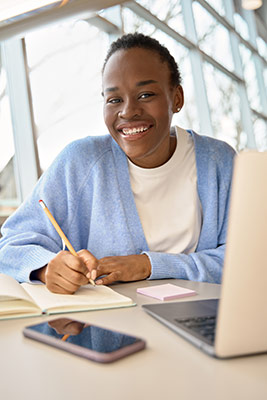 woman-researching-what-is-an-overfunded-life-insurance-policy Woman using her laptop to look up ‘what is an overfunded life insurance policy’ as she works on her retirement plan in a notebook