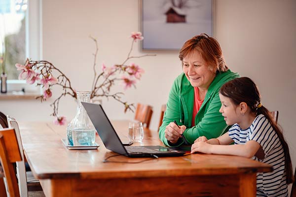 Granddaughter helping her grandmother use a laptop to look up ‘what is straight life insurance’
